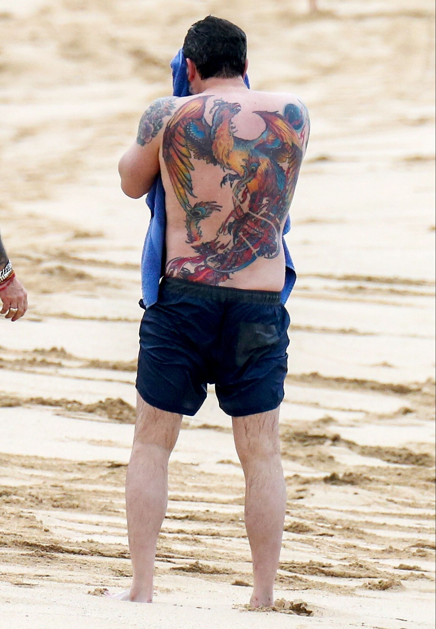 ben affleck on the beach, with a back tattoo of a colourful dragon